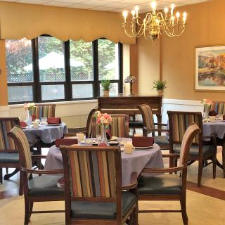A cozy dining room with elegantly set tables and a chandelier.