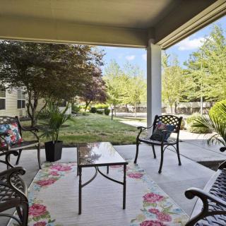 A cozy patio with outdoor seating surrounded by a lush garden.
