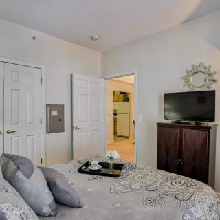 A cozy bedroom featuring a neatly made bed, TV on a dresser, and stylish decor.