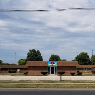 A view of a brick building surrounded by greenery under a cloudy sky.