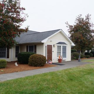 A suburban house with a well-maintained lawn and trees in the front yard.