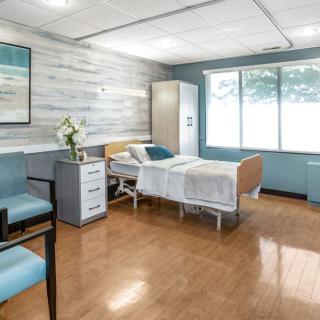 A clean and bright hospital room with a single bed and comfortable furnishings.