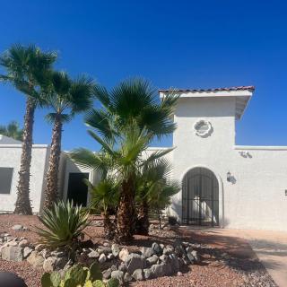 A white house with palm trees and desert landscaping on a sunny day.