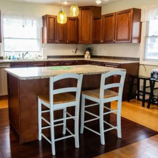 A modern kitchen with wooden cabinets and an island with bar stools.
