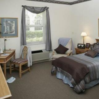 A cozy bedroom with a bed, desk, and chair next to a window.