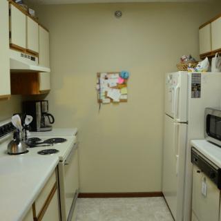 A compact kitchen with essential appliances, including a fridge, microwave, and coffee maker.