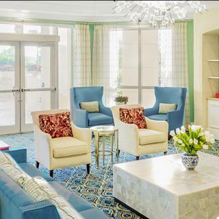 A stylish living room with blue chairs, white sofas, and a contemporary chandelier.