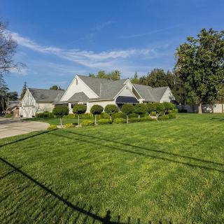 A well-maintained suburban house with a large green lawn and surrounding trees.