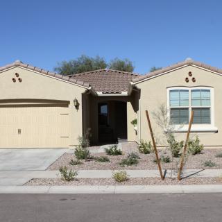A single-story suburban house with a desert landscape front yard.