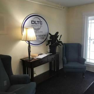 A cozy office waiting area with chairs, a lamp, and a sign on the wall.