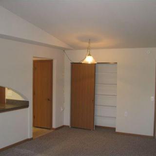 An empty room with a light fixture, closet, and doorway.