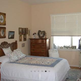 A cozy bedroom with a single bed, decorated with framed pictures and a chest of drawers.