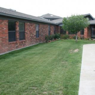 A brick building with a grassy yard and a sidewalk in front.