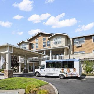 A modern residential building with a shuttle bus parked at the entrance.