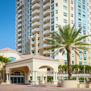 Modern condominium with palm trees in a sunny urban setting.