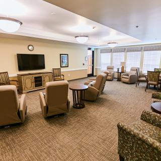 A well-lit common living room area with comfortable seating and a television.