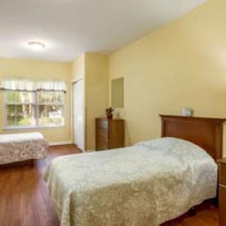 A simple bedroom with two beds and wooden flooring.
