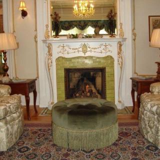 A traditionally decorated living room with a luxurious fireplace, elegant furniture, and a chandelier.