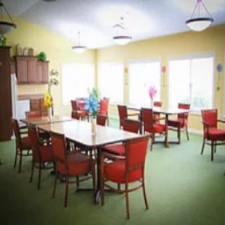 A bright dining room with red chairs and large windows.