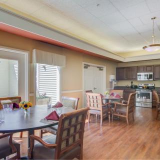 A dining area with multiple tables and chairs, adjacent to a kitchen with modern appliances.