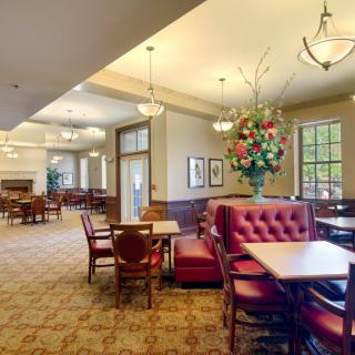 A spacious lobby area with elegant furnishings, featuring a large table with red cushioned seating and stylish lighting.
