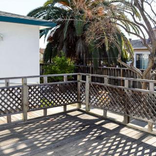 A sunny outdoor deck with wooden railings and a view of palm trees.