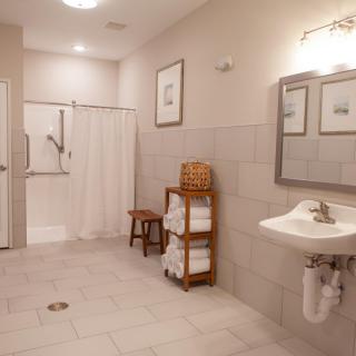 A spacious and accessible bathroom with a walk-in shower, sink, and towel storage.