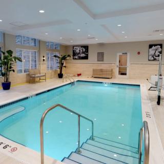 A modern indoor swimming pool with a relaxing atmosphere, featuring comfortable seating and elegant decor.