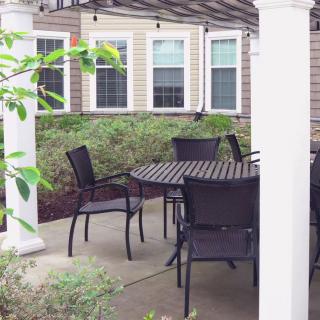 An outdoor patio area with a table and chairs under a pergola.
