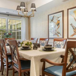 A well-decorated dining room featuring a set table, elegant chairs, and framed artwork on the walls.