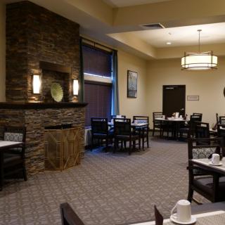 A cozy restaurant interior with neatly arranged tables and chairs, featuring a stone fireplace.