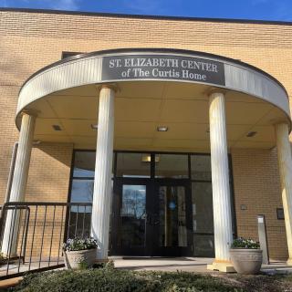 The entrance of a building with columns and a sign overhead.
