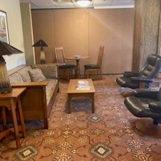 A cozy living room with a sofa, armchairs, and a coffee table on a patterned carpet.