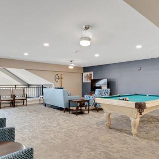 A modern game room featuring a pool table and comfortable seating.
