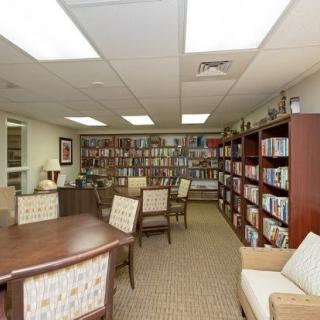 A cozy library room with bookshelves, tables, and chairs for reading.