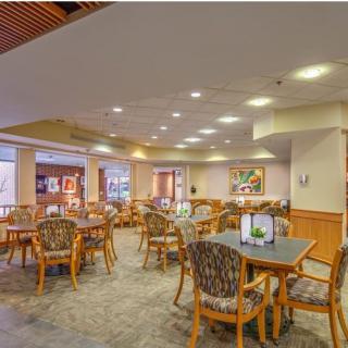 An inviting dining area with wooden tables and chairs, brightly lit with cozy decor.