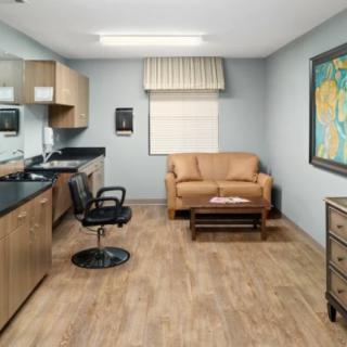 A neatly organized office space with a desk, chair, and sofa, featuring artwork on the wall.