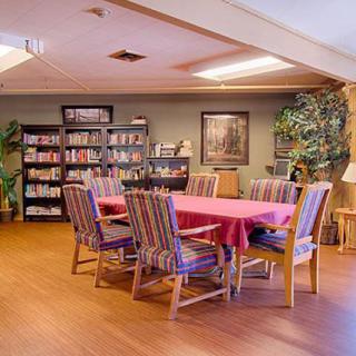 A cozy dining area with a table and chairs surrounded by bookshelves and indoor plants.