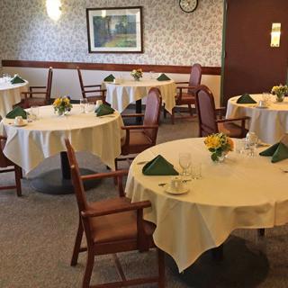 A cozy dining room with elegantly set tables and chairs, ready for guests.