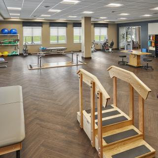 A spacious and well-equipped physical therapy clinic with various rehabilitation tools and equipment.