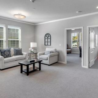 A modern living room with a sofa and armchair, featuring a neutral color scheme and ample natural light.