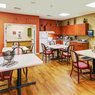 A communal dining and kitchen area with tables, chairs, and wooden flooring.