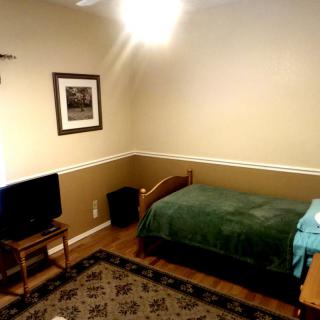 A minimalist bedroom with a single bed, television, and framed picture.