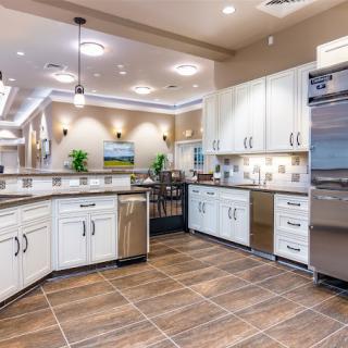A spacious modern kitchen with white cabinets, stainless steel appliances, and a tile floor.