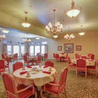 A spacious dining room with elegant chandeliers and red upholstered chairs.