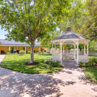 A peaceful garden featuring a white gazebo surrounded by lush greenery and winding pathways.