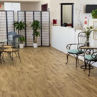 A cozy waiting room with decorative chairs, plants, and wooden flooring.