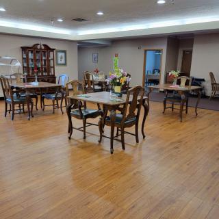 A spacious dining room with wooden floors and elegant furniture arranged neatly.