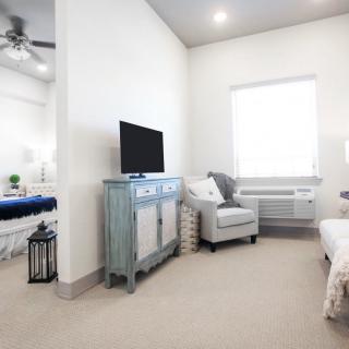 A modern living space with a TV, chair, and light color scheme.