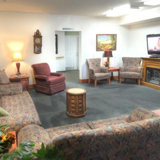 A cozy living room with sofas, chairs, a television, and warm lighting.